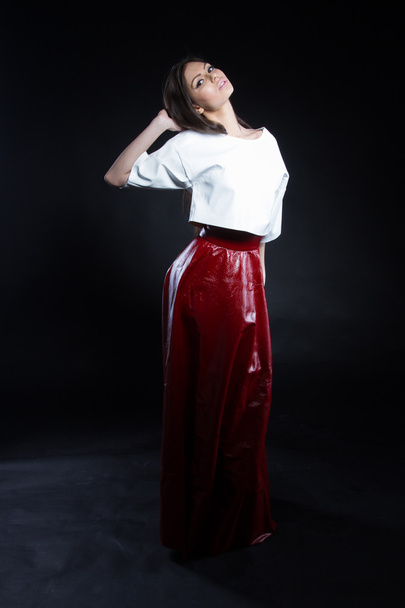 Belle jeune fille en chemisier blanc et une longue jupe rouge sur fond noir
. - Photo, image