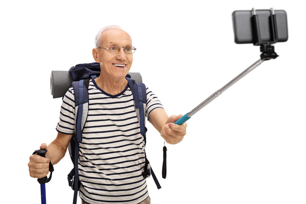 Vanhempi patikoija ottaa selfien kepillä
 - Valokuva, kuva