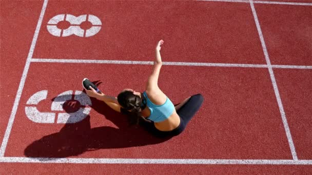 Śledzić kobieta lekkoatletka runner rozgrzewkę przed uruchomieniem na stadionie, widok z góry - Materiał filmowy, wideo
