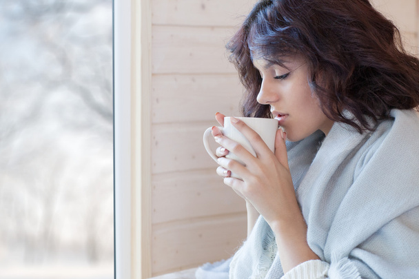 beautiful brunette woman covered in blanket with cup of coffee  - Valokuva, kuva