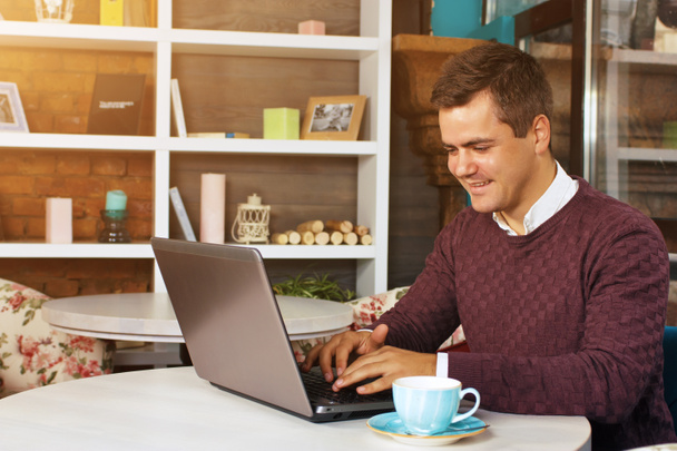 Gülümseyerek mutlu bir genç adam ve onun laptop üzerinde çalışır - Fotoğraf, Görsel