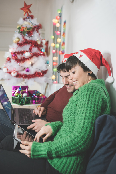 coppia con cappelli Babbo Natale utilizzando il computer
 - Foto, immagini