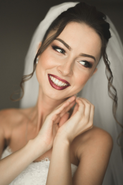 Beautiful young bride with makeup and hairstyle in bedroom, newlywed woman final preparation for wedding. Happy girl waiting groom. Portrait soft focus - Φωτογραφία, εικόνα