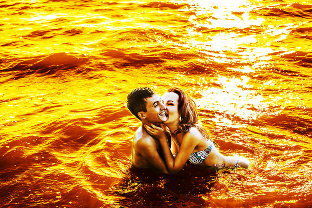 pretty young adult couple embracing, kissing  in  sea against water texture. H - Photo, Image