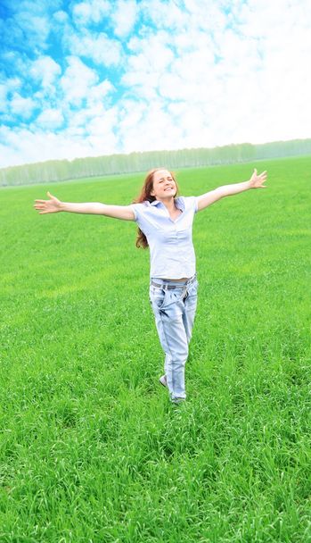 meisje permanent op groen gras in het veld - Foto, afbeelding