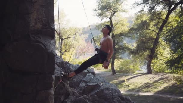 Climber jumping from cliff while hanging on rope - Materiał filmowy, wideo