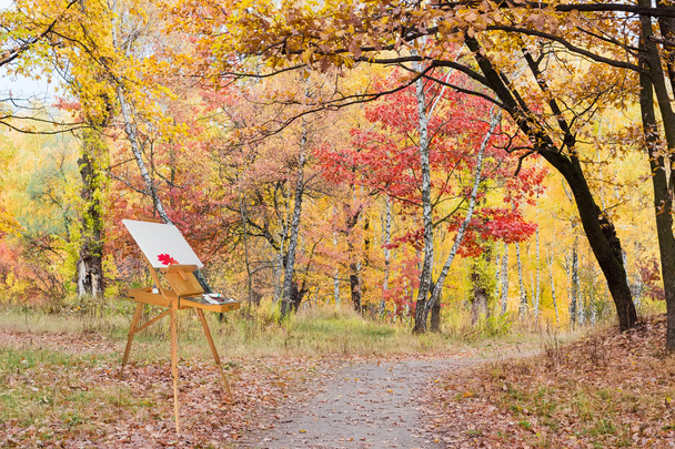 Chevalet en bois avec toile vide dans la forêt d'automne
 - Photo, image