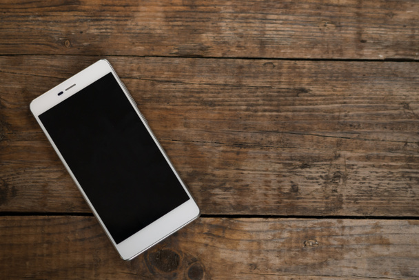 Smartphone mit leerem Bildschirm auf Holztisch liegend. - Foto, Bild