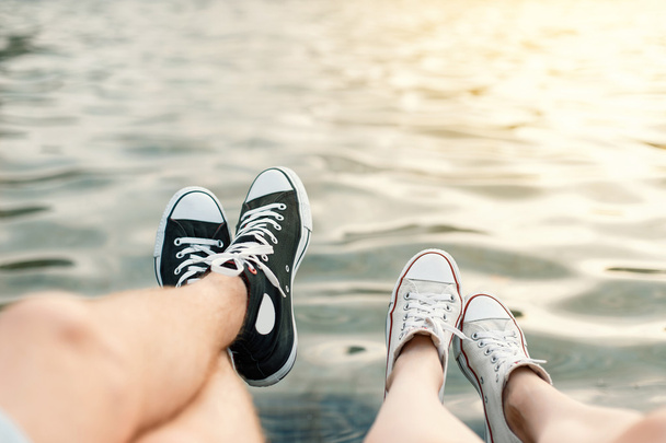 Young couple lying on the beach. Legs with sneakers near water - Foto, Imagem