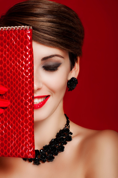 Mooi meisje met een rode portemonnee. Make-up. Model met rode lippenstift - Foto, afbeelding