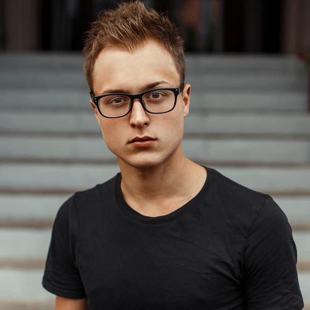Jeune homme beau avec des lunettes dans une chemise noire
. - Photo, image