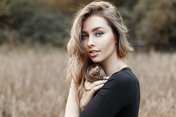 Portrait of a young woman in a black shirt on a background of nature - Photo, Image