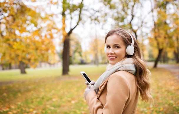 woman with smartphone and earphones in autumn park - Zdjęcie, obraz