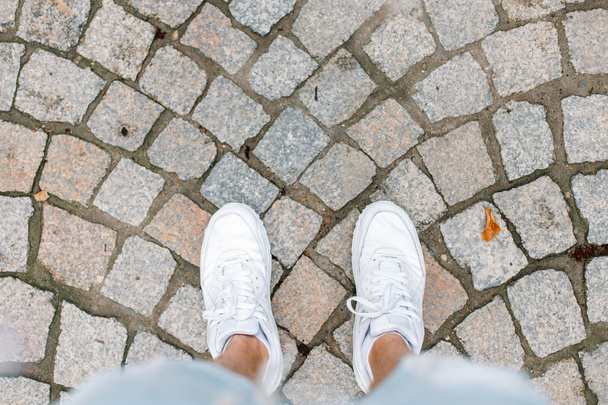 Young man traveling on summer vacation. White sneakers on tile. - Photo, Image