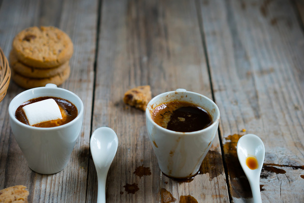 Two cups of coffee with marshmallow and cookie crumbs on a wooden background. - Fotó, kép