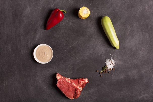 Raw meat steak on black chalkboard with vegetables - Foto, Bild