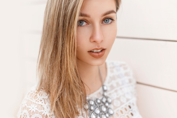 Portrait of a beautiful blond girl with blue eyes on the background of a wooden wall. - Photo, Image