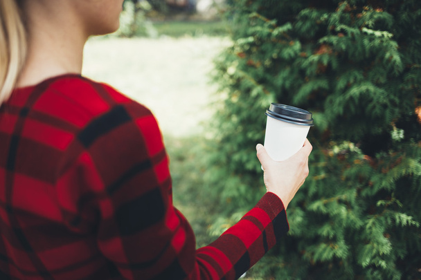 Girl offers a cup of coffee in park - Foto, afbeelding