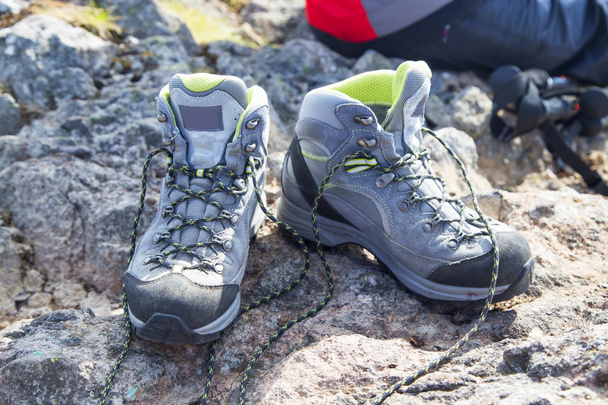 Hiking boots with trekking sticks on the mountain peak - Photo, Image