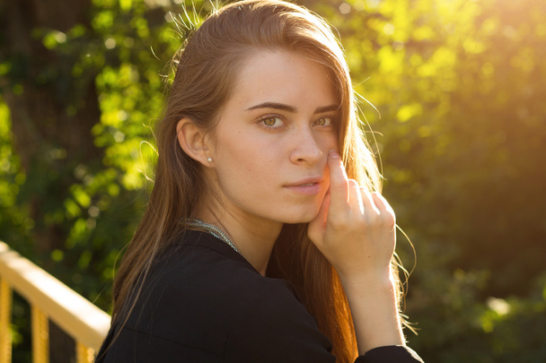 junge Frau auf dem Hintergrund von Bäumen und Sonnenlicht - Foto, Bild