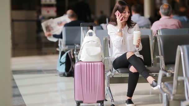 Pasażer linii lotniczej na lotnisku czeka na samolot. Biała kobieta szuka czasu w poczekalni - Materiał filmowy, wideo
