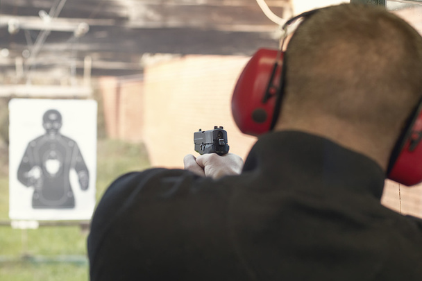Shooting with a pistol. Man aiming pistol in shooting range. - Фото, изображение