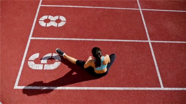 Nízký úhel trati běžec sportovec žena rozcvičení před spuštěním na stadionu, pomalý pohyb - Záběry, video