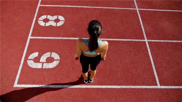 Alacsony szög pályán futó sportoló nő bemelegítés előtt futás-on egy stadion, lassú mozgás - Felvétel, videó
