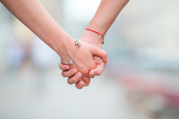 Close up of girl and boy holding each other hands in city outdoor - Photo, Image