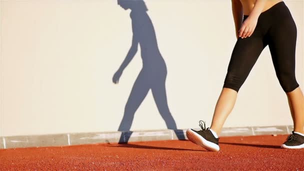 Corredor de pista mujer y su sombra en una pared preparándose para correr, cámara lenta
 - Metraje, vídeo