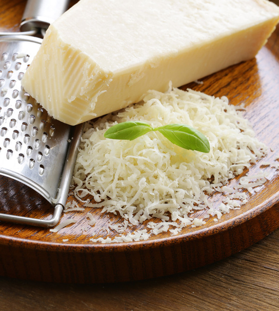 geraspte en hele Parmezaanse kaas op een houten tafel - Foto, afbeelding
