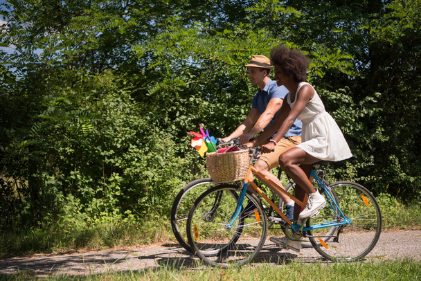 Νεαρό ζευγάρι πολυεθνική έχοντας ένα ποδήλατο βόλτα στη φύση - Φωτογραφία, εικόνα