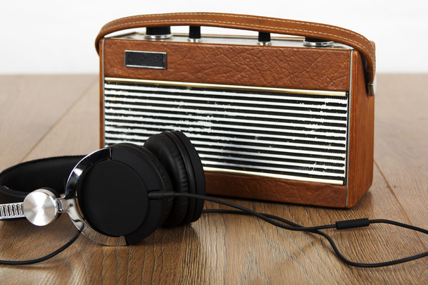 Ακουστικά και παλιό ραδιόφωνο σε ξύλινη επιφάνεια - Φωτογραφία, εικόνα