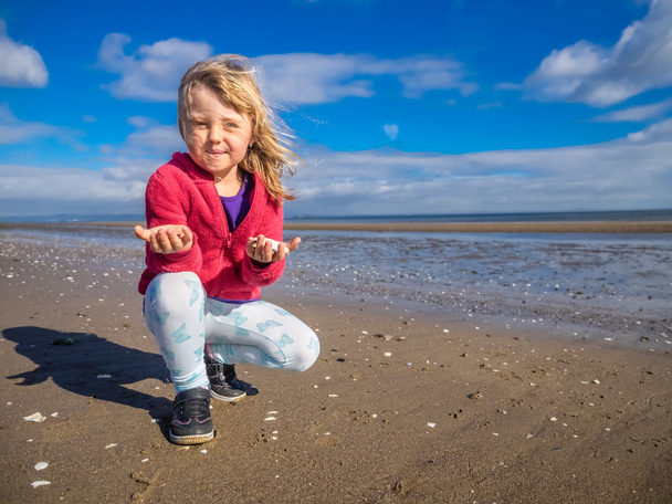 Dziewczyna pokazuje małże zbierane na plaży - Zdjęcie, obraz