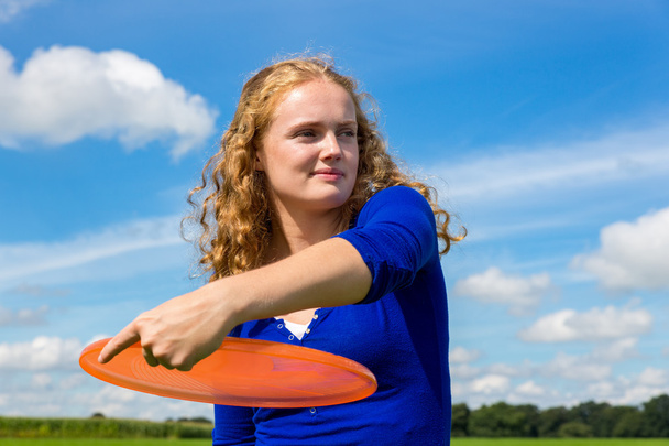 Joven holandés mujer lanzando frisbee naranja
 - Foto, Imagen