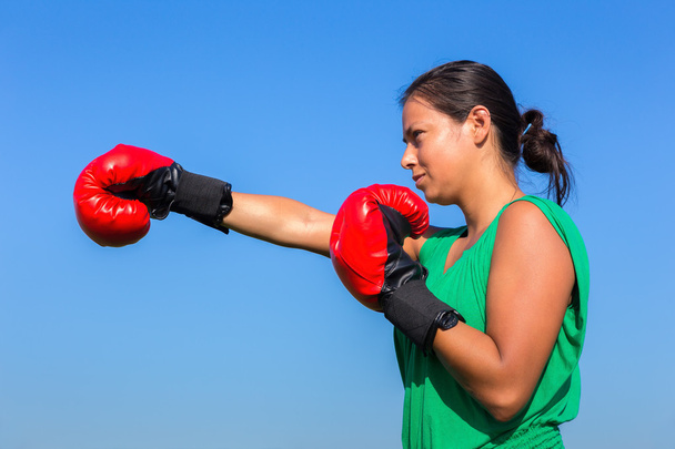 Mladá žena nosí červené Boxerské rukavice s modrou oblohou - Fotografie, Obrázek