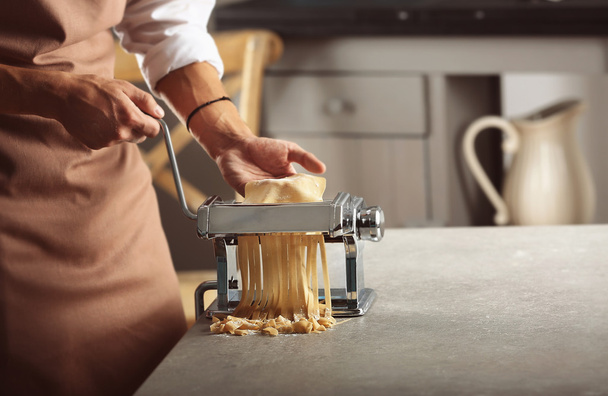 Man using pasta machine to prepare tagliatelle, close up view - Photo, image