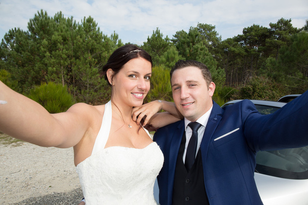 Beautiful young wedding couple outside in nature doing a selfie - Photo, Image
