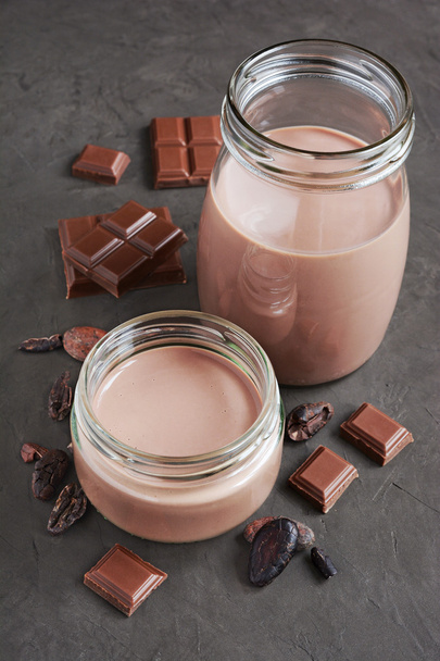 Chocolate milk with pieces of chocolate bar and cacao beans  - Zdjęcie, obraz