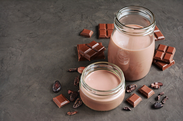 Chocolate milk with pieces of chocolate bar and cacao beans  - Φωτογραφία, εικόνα