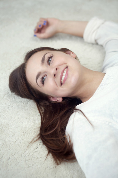 young woman lying on carpet and smiles - Photo, Image