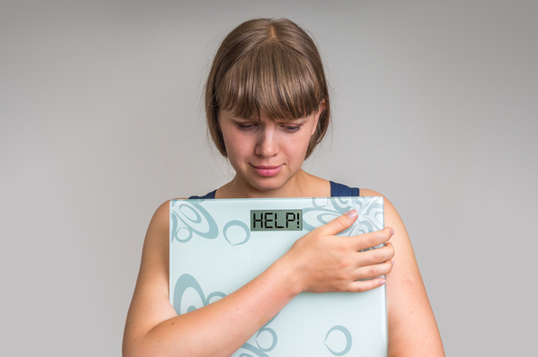 Mulher com sobrepeso frustrado segurando balanças digitais com AJUDA
! - Foto, Imagem