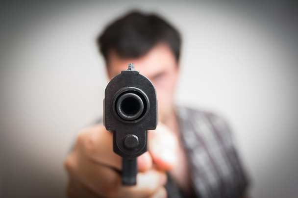 Gek jongeman die gericht zijn pistool op je - Foto, afbeelding