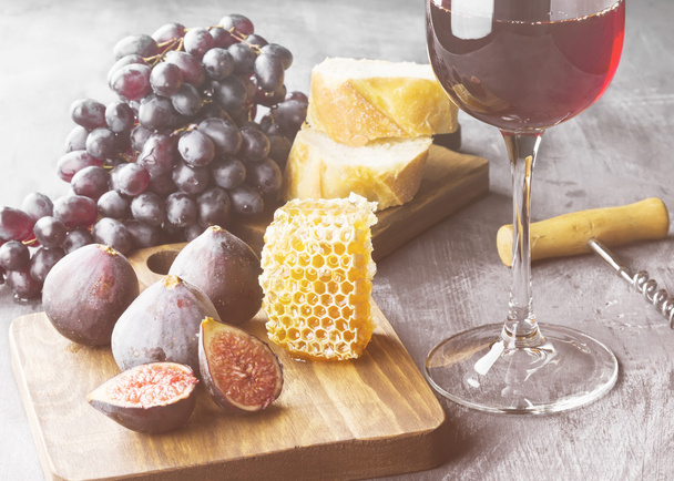 Red wine with fig, dark grapes, honey, bread on a dark backgroun - Foto, Bild