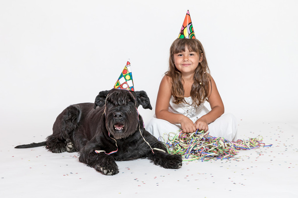 Cute little girl with lying black dog on the white  - Foto, Imagen