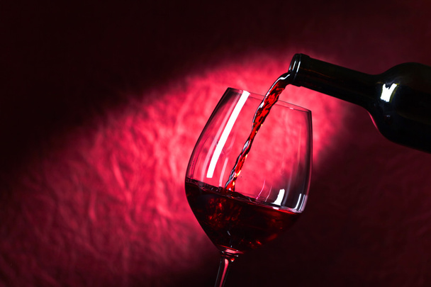 Garrafa e copo de vinho tinto em um fundo escuro
 - Foto, Imagem