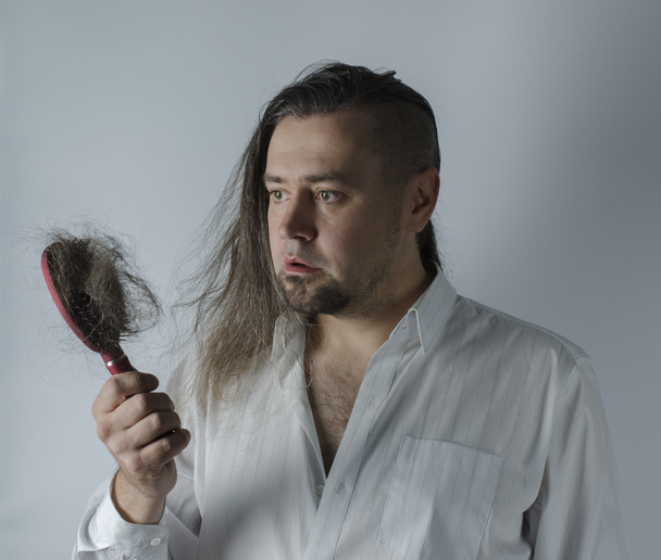 man looking at  hairbrush - Valokuva, kuva
