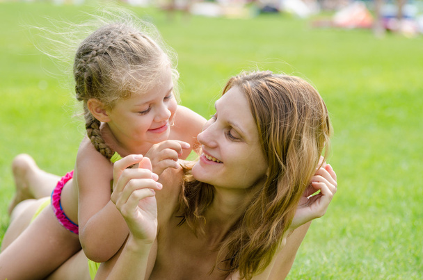Mamma e figlia si divertono sdraiati su un prato verde in estate
 - Foto, immagini