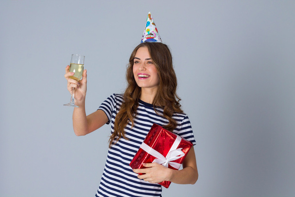 Woman in celebration cap holding a present and a glass - 写真・画像