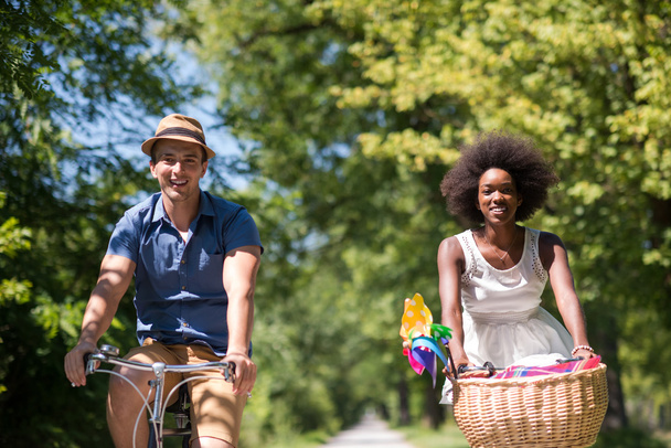 Jovem casal multiétnico ter um passeio de bicicleta na natureza
 - Foto, Imagem